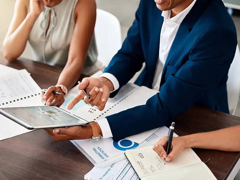 Person pointing at a tablet during a meeting